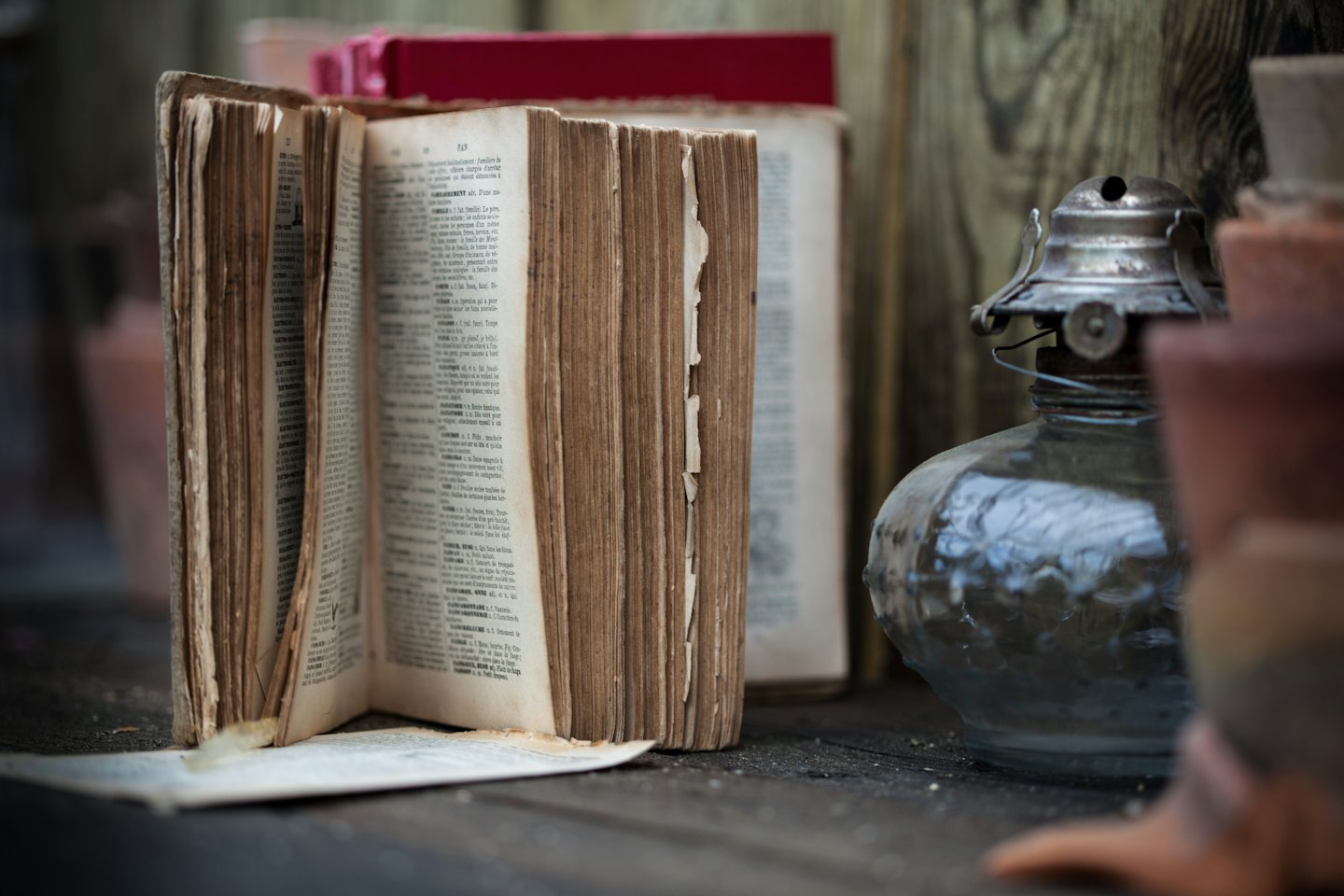 Altes offenes Buch und Öllampe auf einem Holztisch.