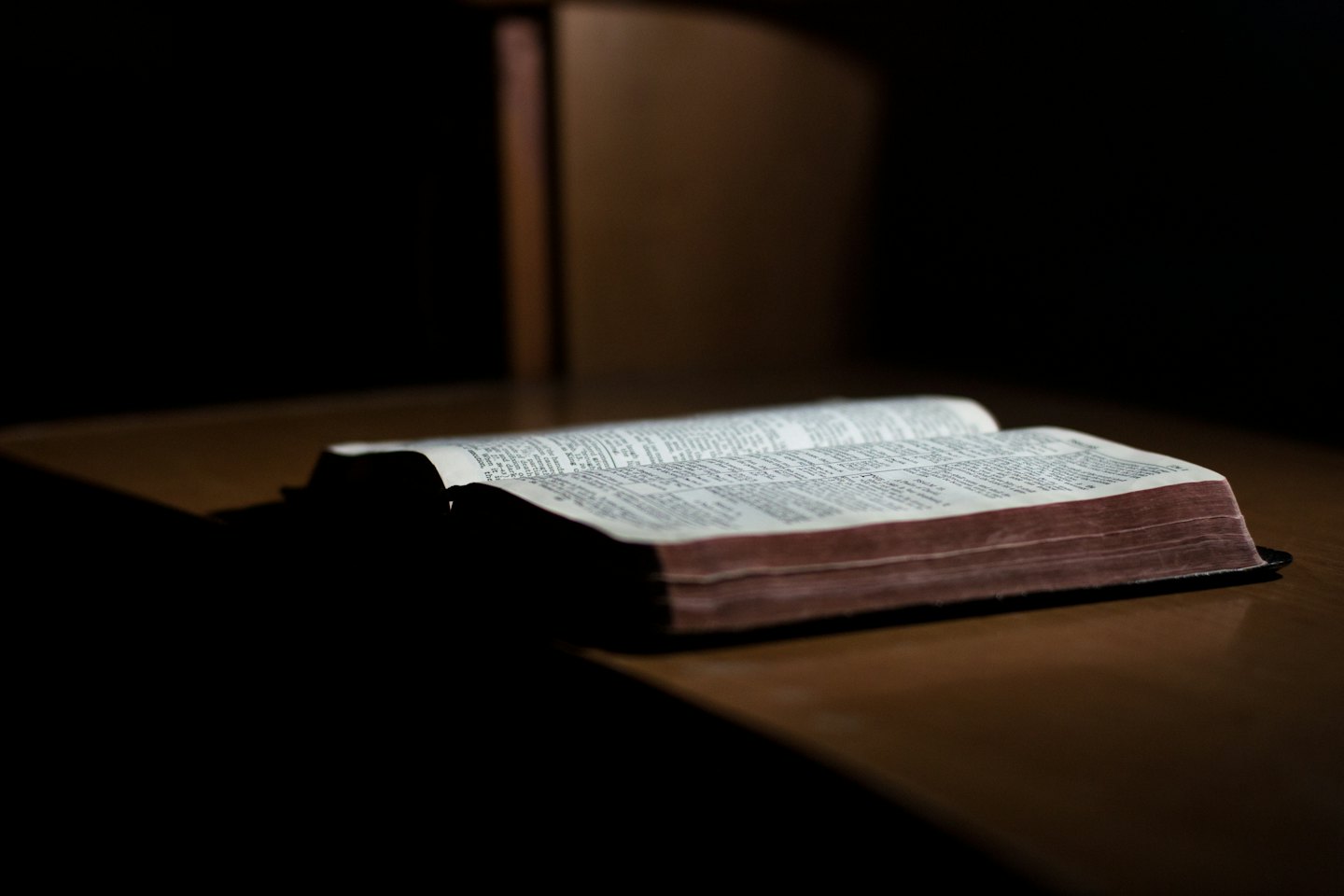 Offenes Buch mit beleuchteten Seiten auf dunklem Holz.
