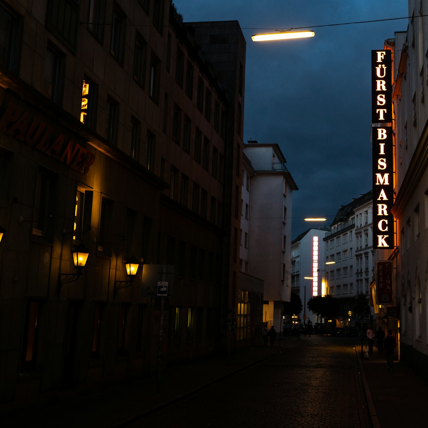 Leuchtende Neonschilder glühen nachts über einer Stadtstraße.